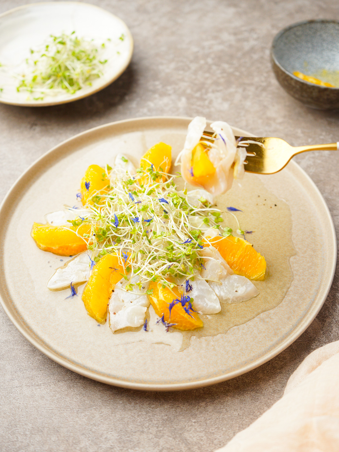 白身魚とオレンジのカルパッチョにスプラウトを添えた前菜