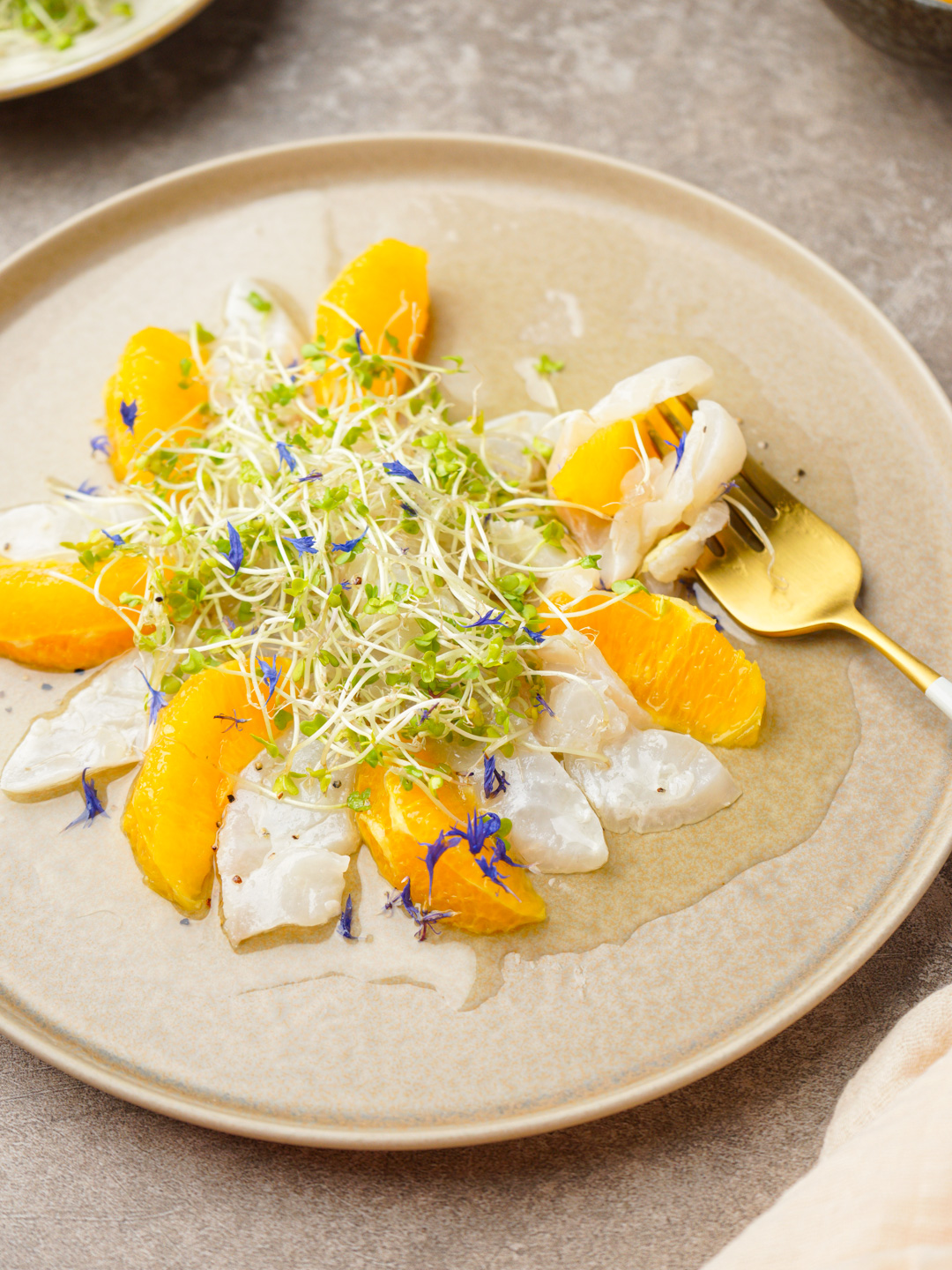 白身魚とオレンジのカルパッチョにスプラウトを添えた前菜